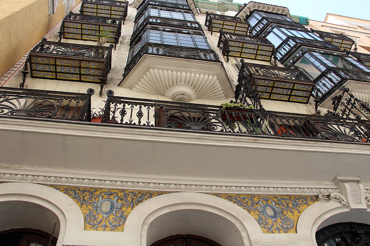 Fachada con balcones de hierro forjado y miradores acristalados en Madrid