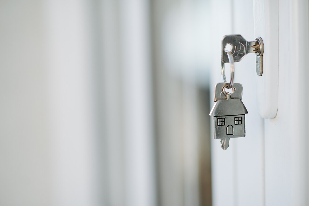 Llave con llavero en forma de casa en la cerradura de una puerta
