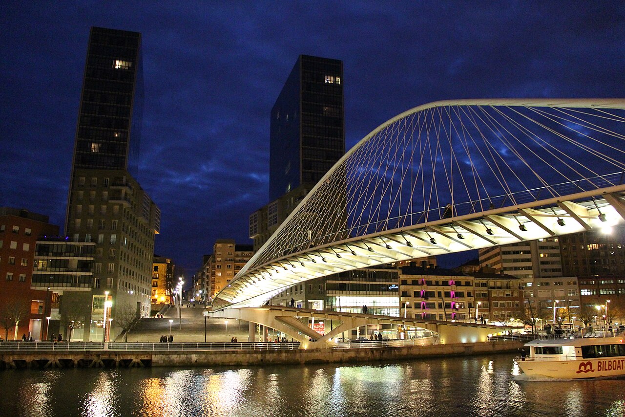 Pasarela Zubizuri y torres de viviendas Isozaki Atea junto a la ría de Bilbao al anochecer