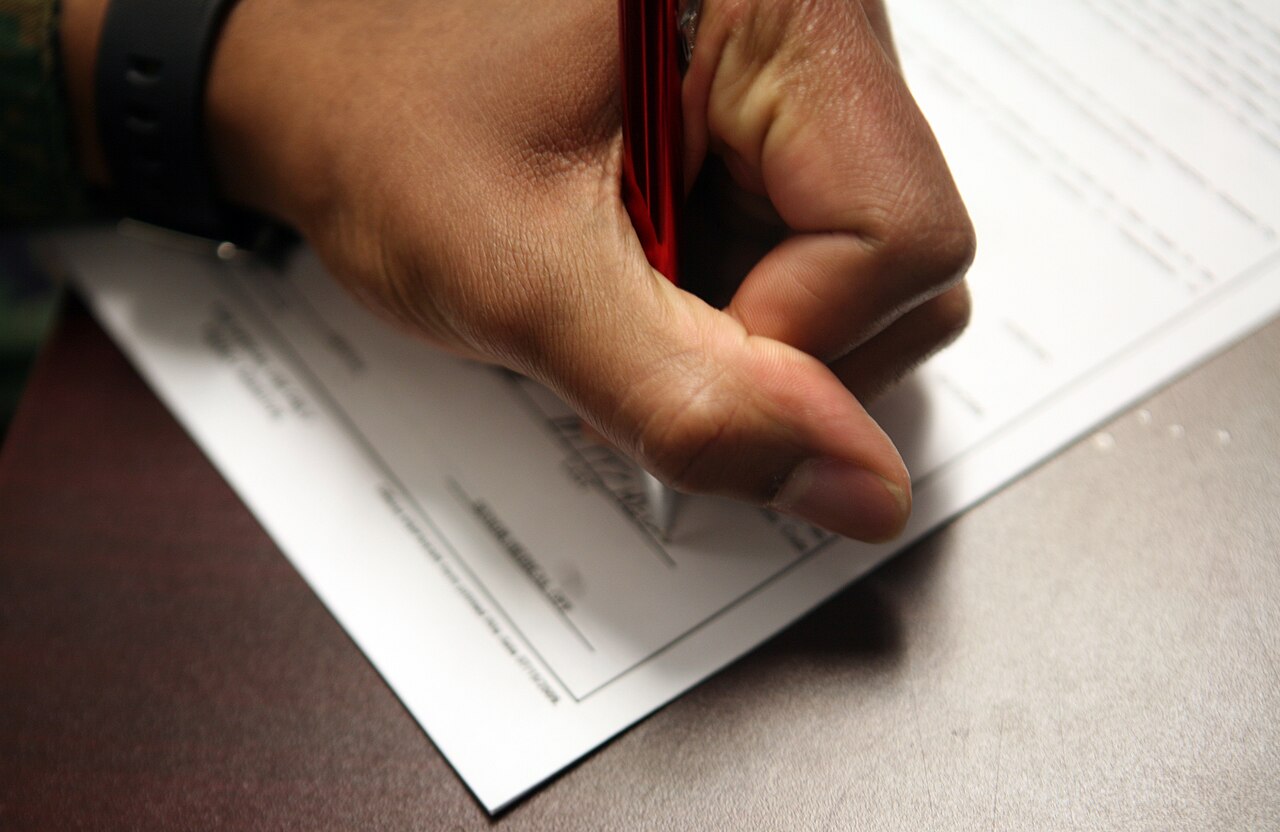 Mano de una persona firmando un documento con un bolígrafo