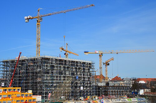 Edificio residencial en construcción cubierto de andamios con varias grúas junto a la estructura