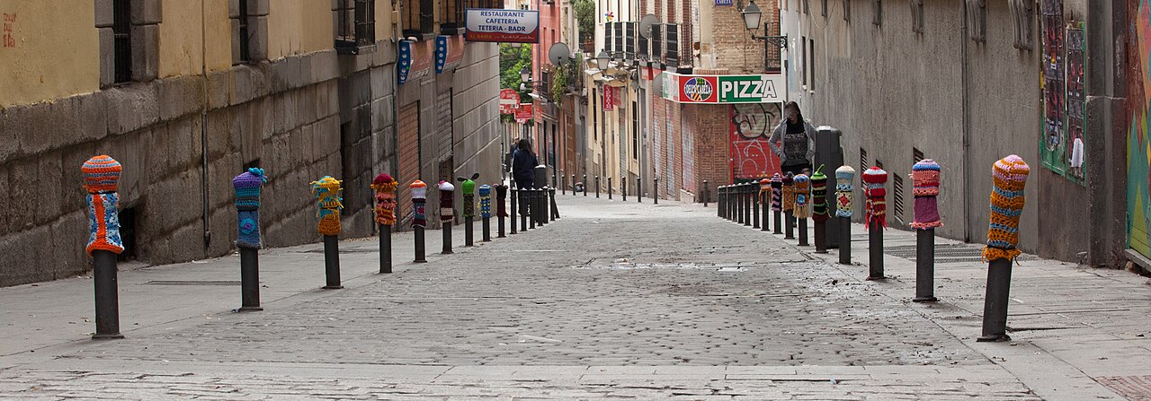 Calle peatonal adoquinada con bolardos tejidos en el barrio de Lavapiés, Madrid