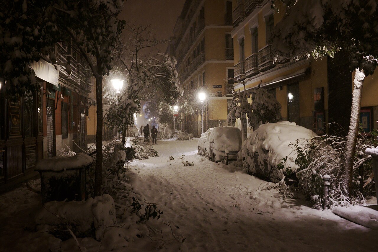 Calle nevada de noche con edificios residenciales y balcones en el barrio de Malasaña, Madrid
